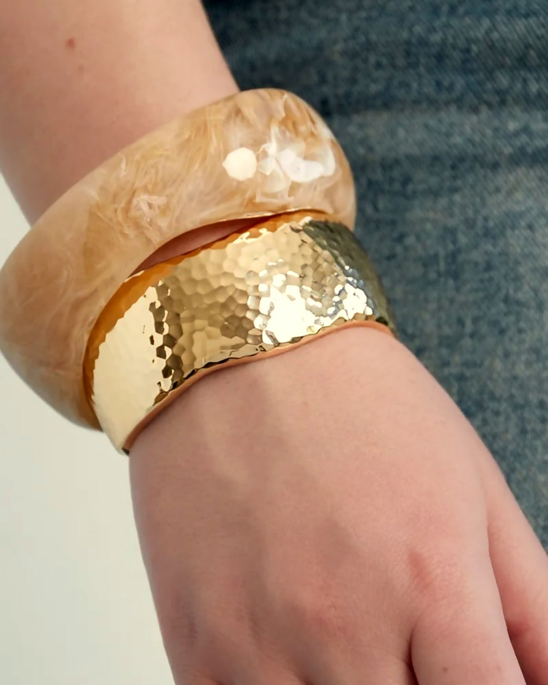 Aurea Armband gedragen, extra brede gehamerde goudkleurige bangle om de pols